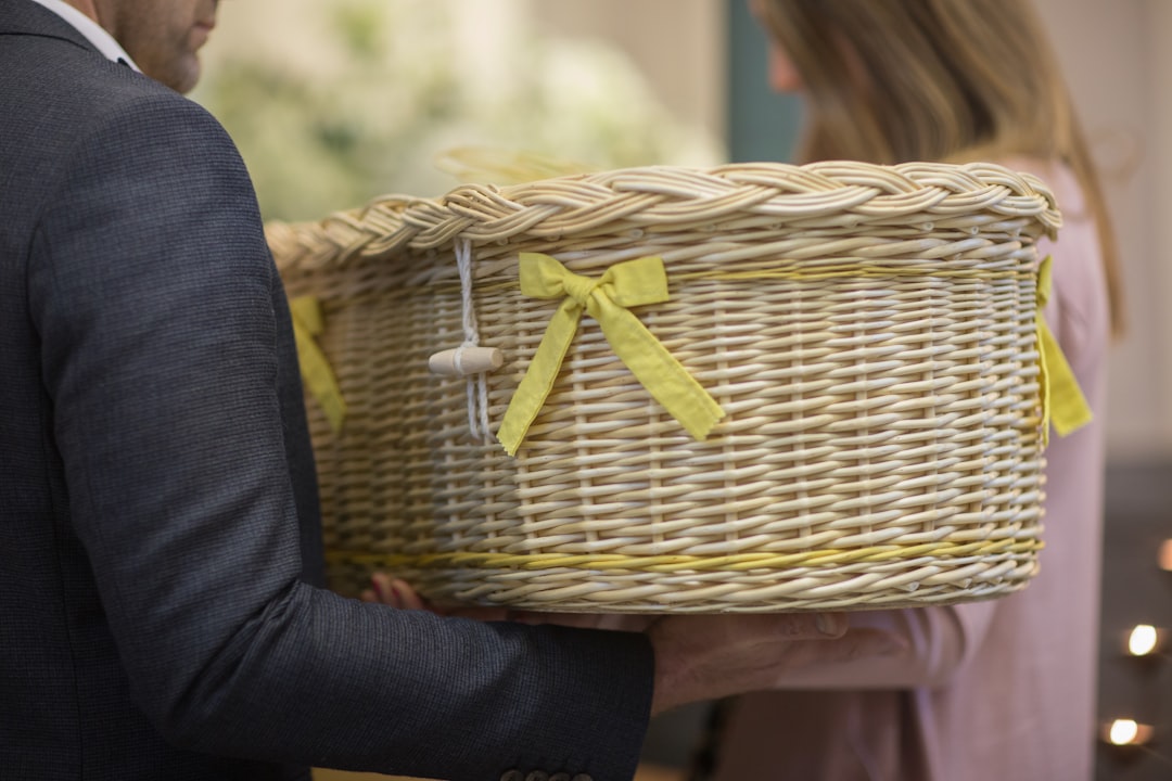 A couple carry a small willow coffin decorated with yellow ribbons